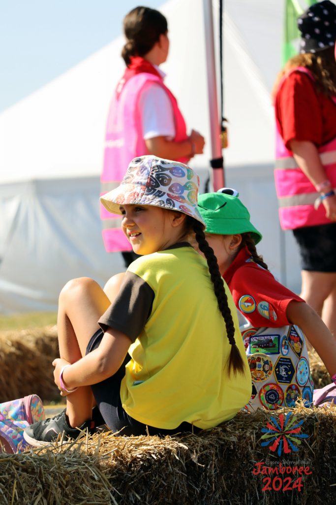 A Brownie and a Rainbow sitting on a hay bale smiling.