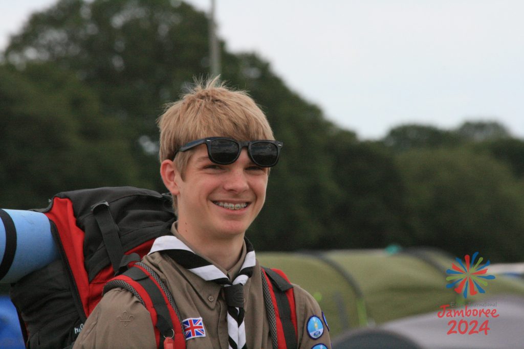 A Scout wearing a backpack smiles for a photo.