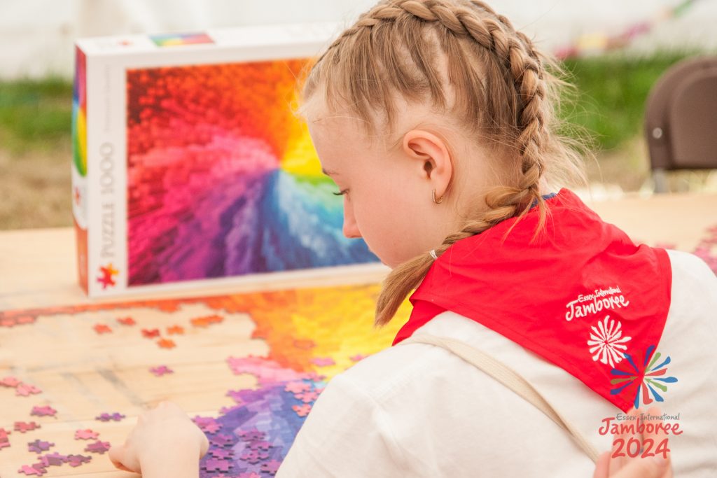 A young person facing away from the camera, doing a colourful puzzle.