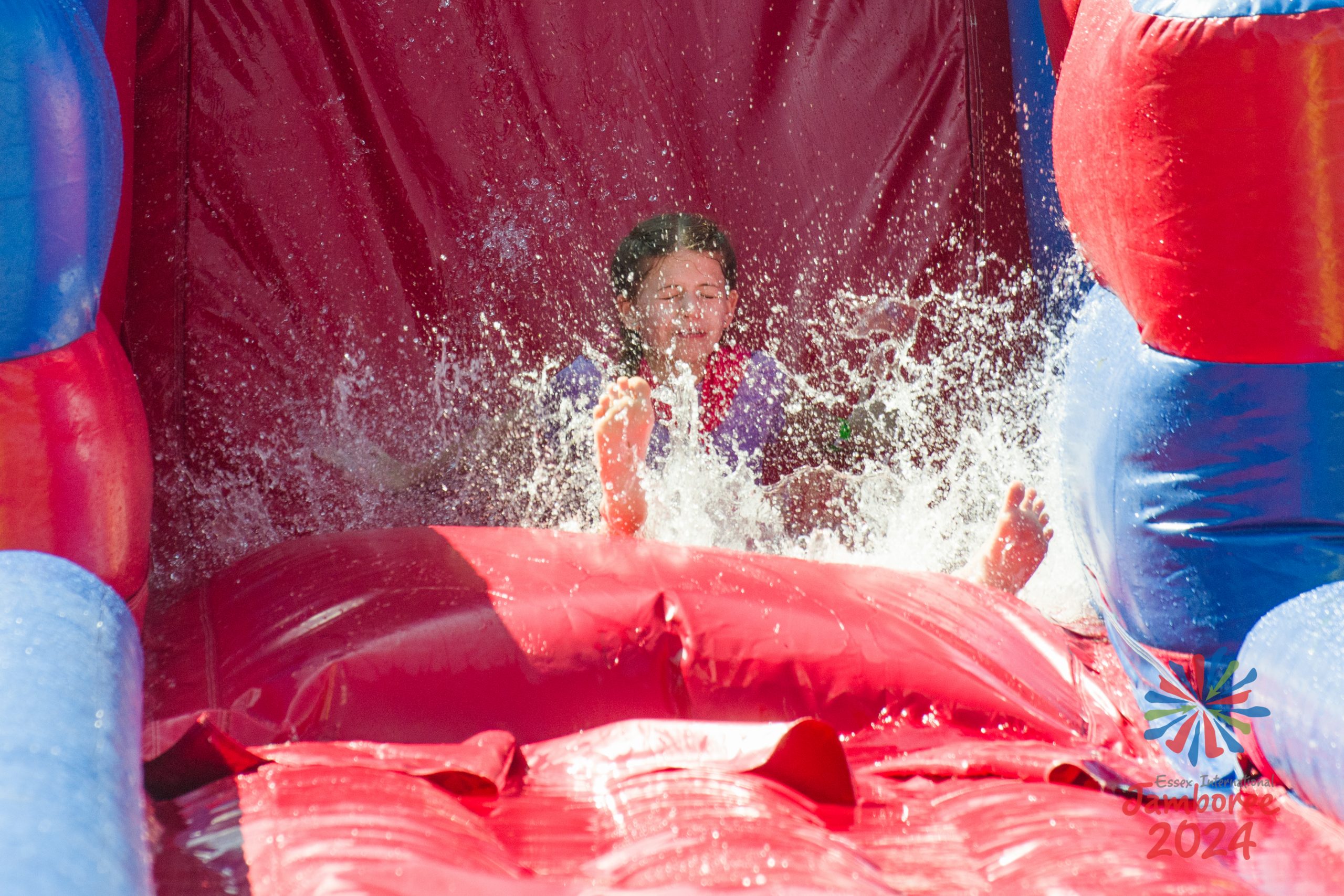 A participants makes as splash as she lands at the bottom of an inflatable water slide