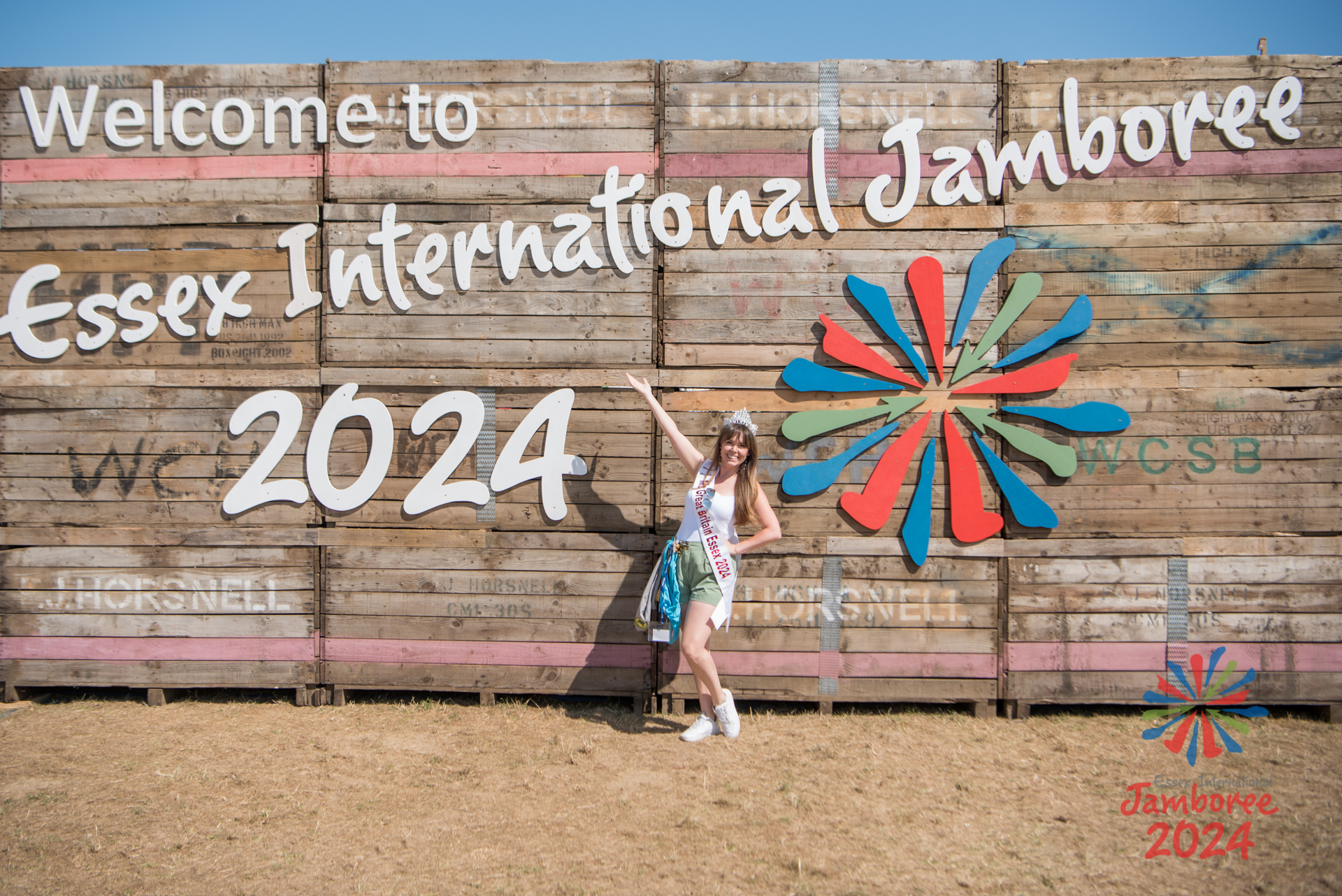 Ms. Essex, wearing her crown and her EIJ necker collection, poses in front of a large EIJ 2024 sign