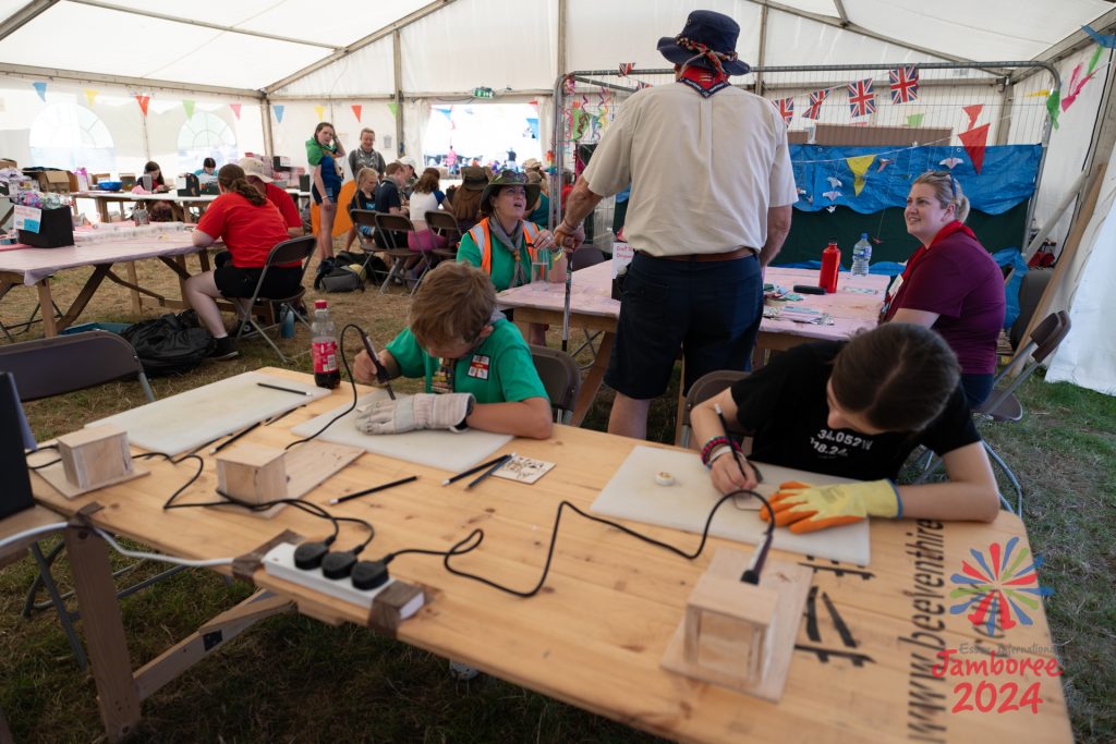 The inside of the craft barn, with lots of young people sitting at tables crafting.