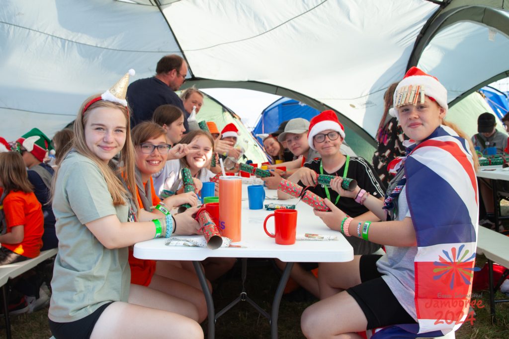 Participants sit around a dining table, waiting to pull Christmas crackers