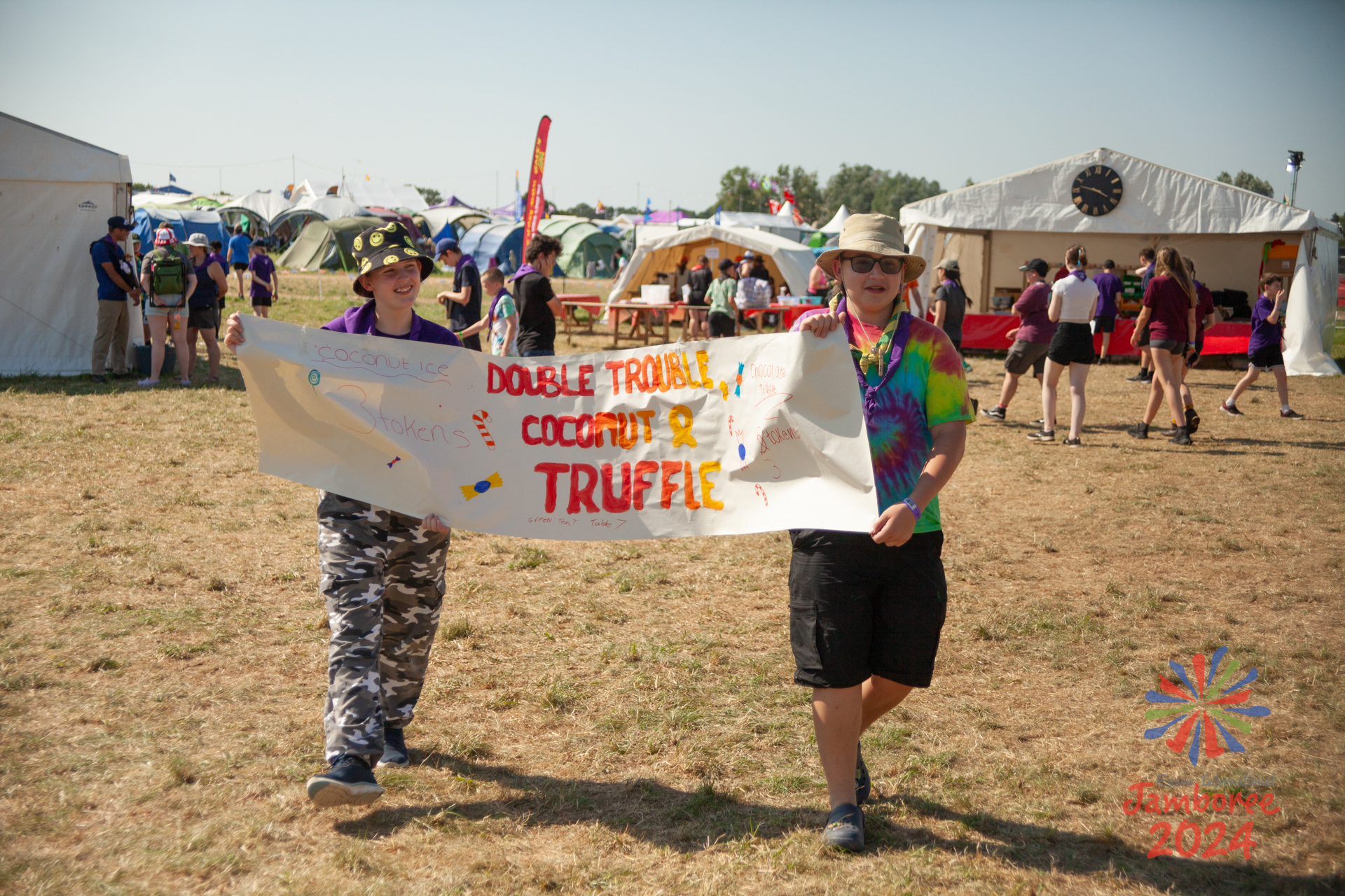 Two young people holding a sign, saying "Double trouble, coconut & truffle".