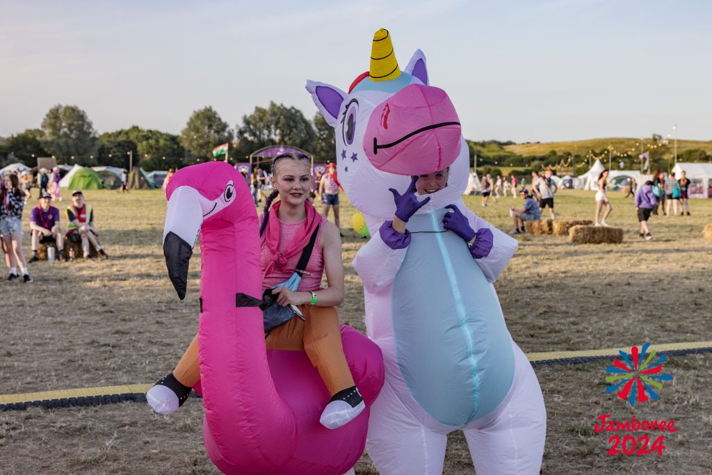 Two girls in inflatable costumes, one of a flamingo, the other a unicorn, enjoy the atmosphere at an outdoor barn dance