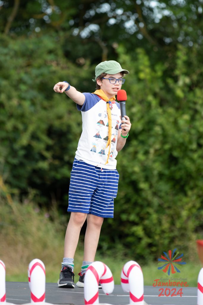 A young person on the stage, advertising their sweets into a microphone. 