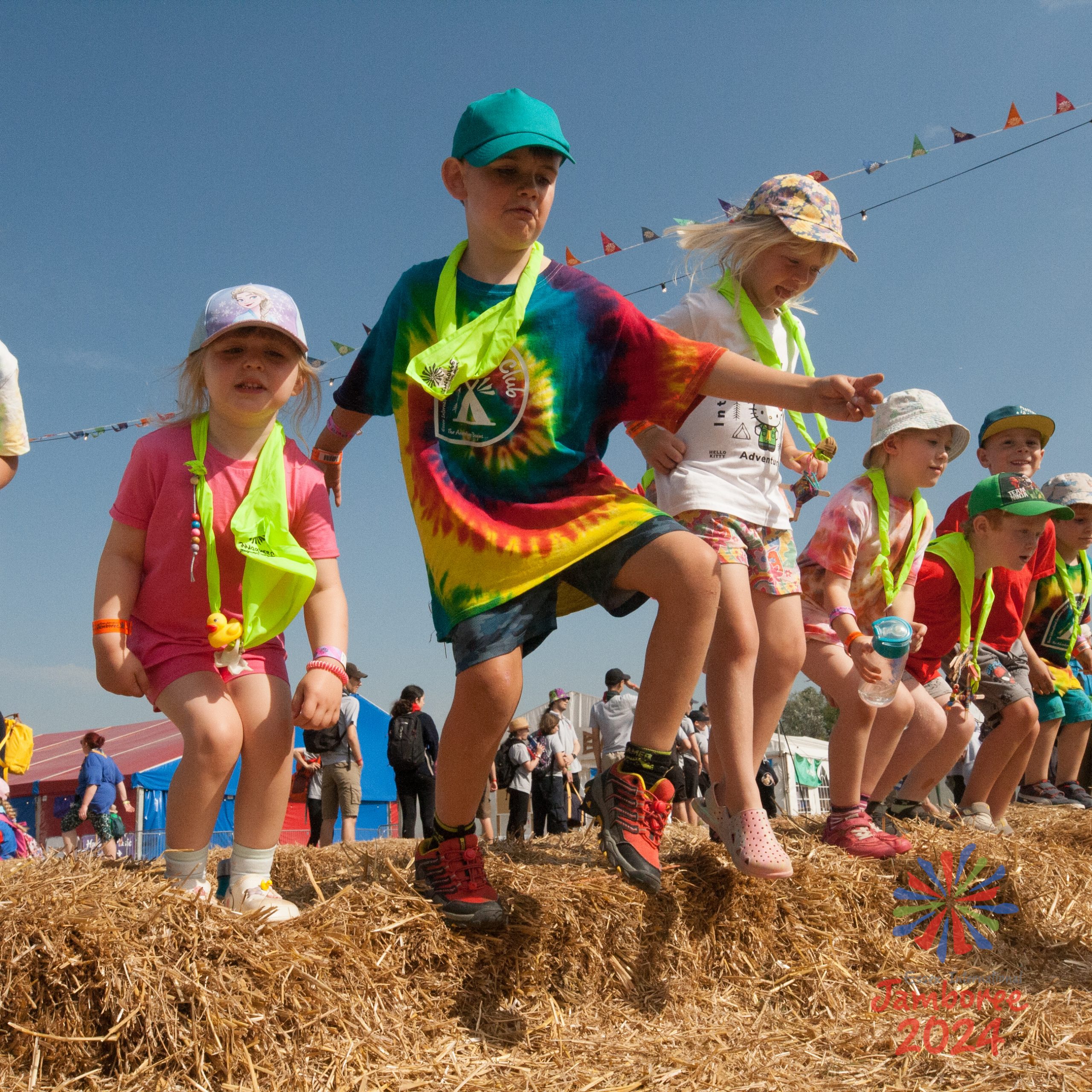 Young members of Noa's club jumping off of a hay bale.