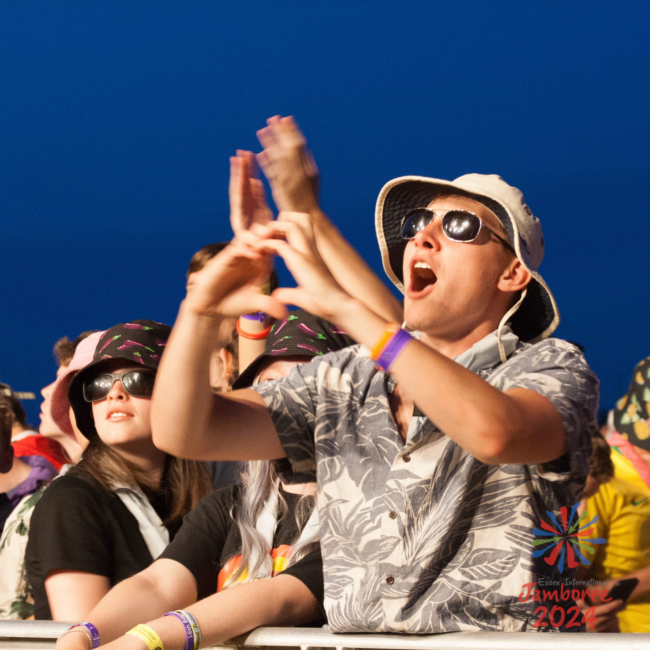 A young person making a heart shape with his hand, in front of the EIJ main stage.