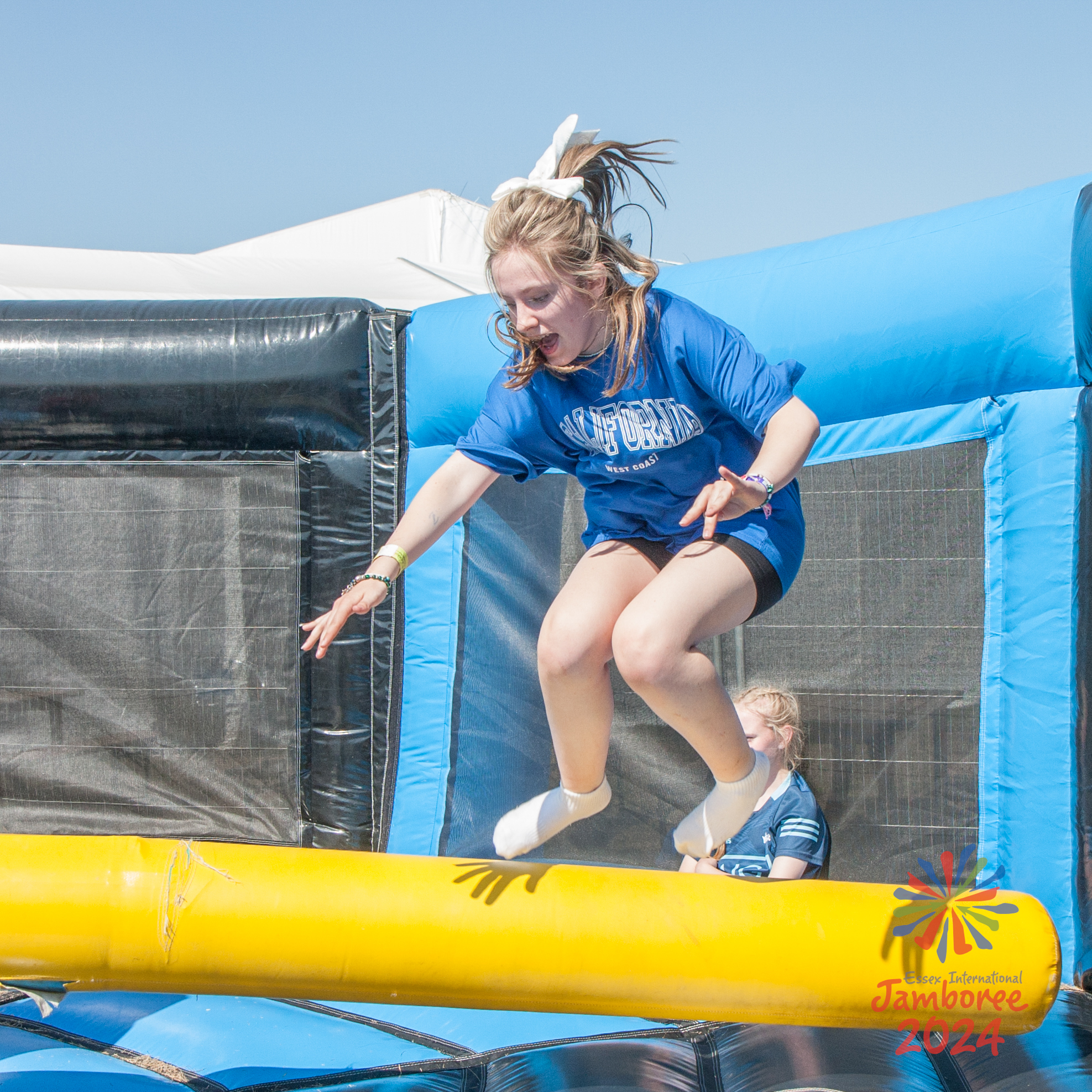 A young person jumping over a swinging bar.