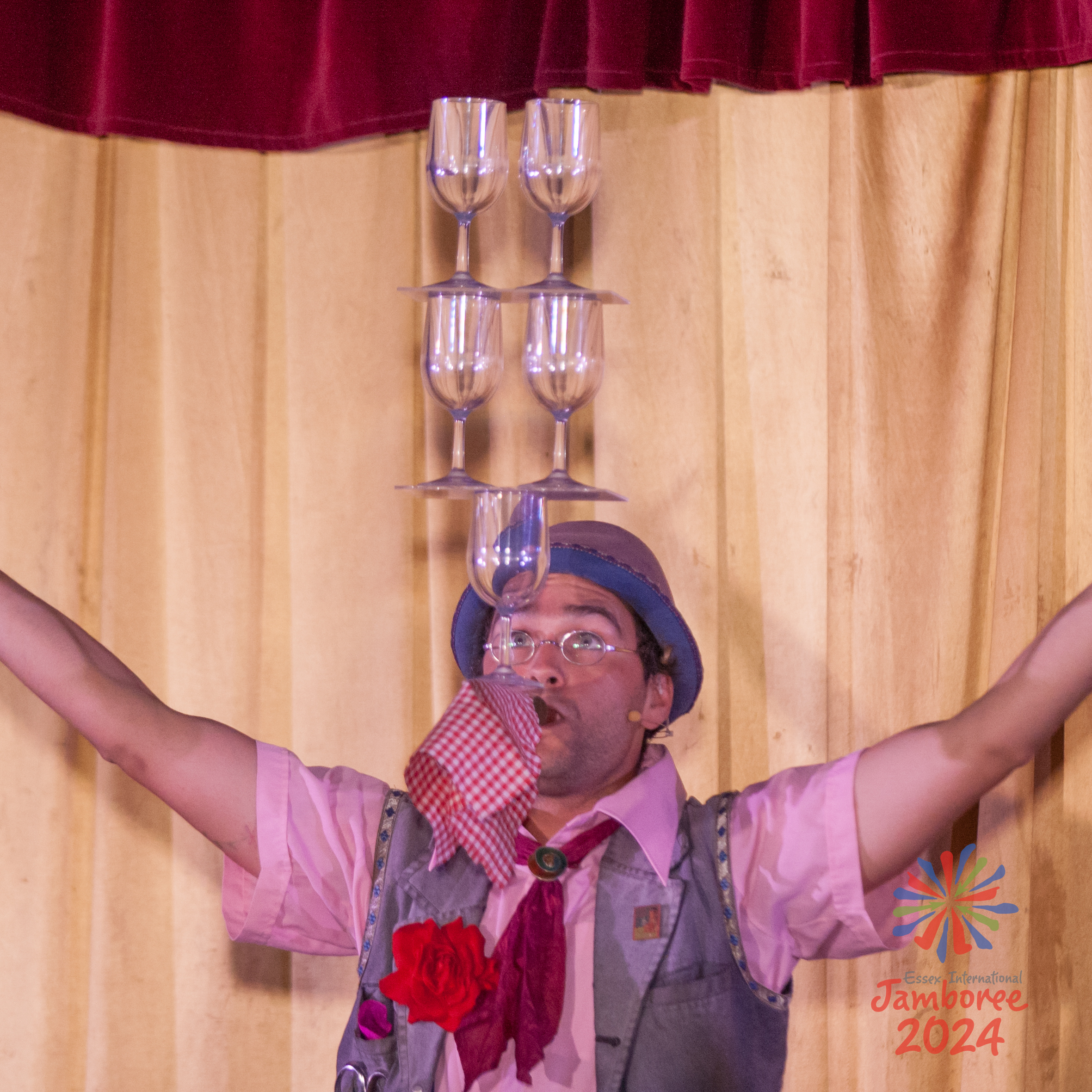 A man balancing a stack of glasses in his mouth.