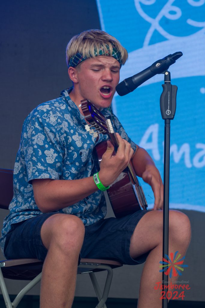 A participant singing into a microphone while playing guitar.