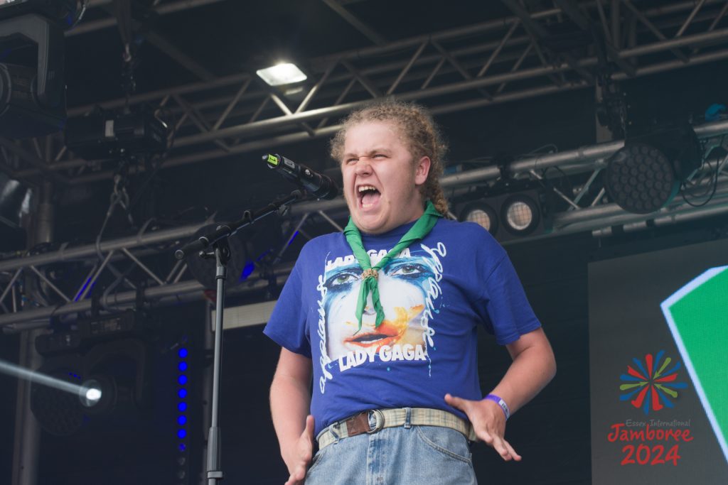 A participant passionately singing innto a standing microphone, wearing a Lady Gaga t-shirt. 