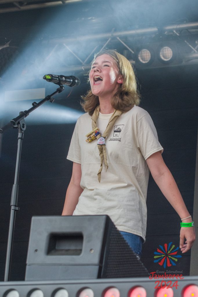 A girl passionately singing into a standing microphone. 