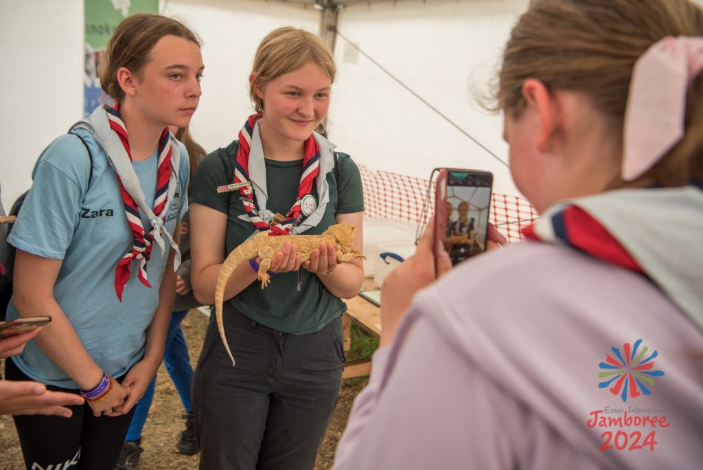 Two participants having their photo taken by a third participant, while holding a reptile.