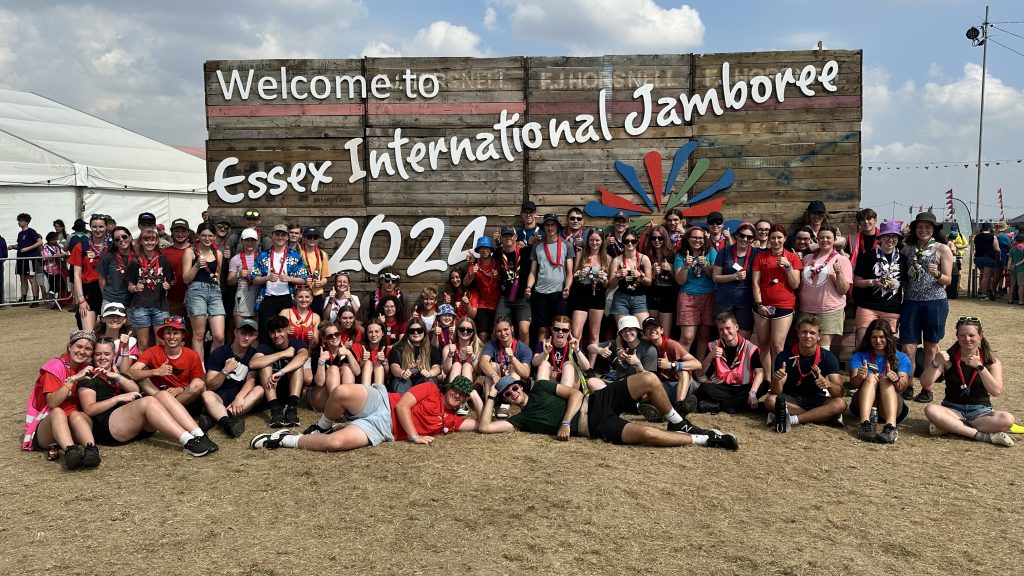 A group of people standing in front of the Essex International Jamboree 2024 sign.