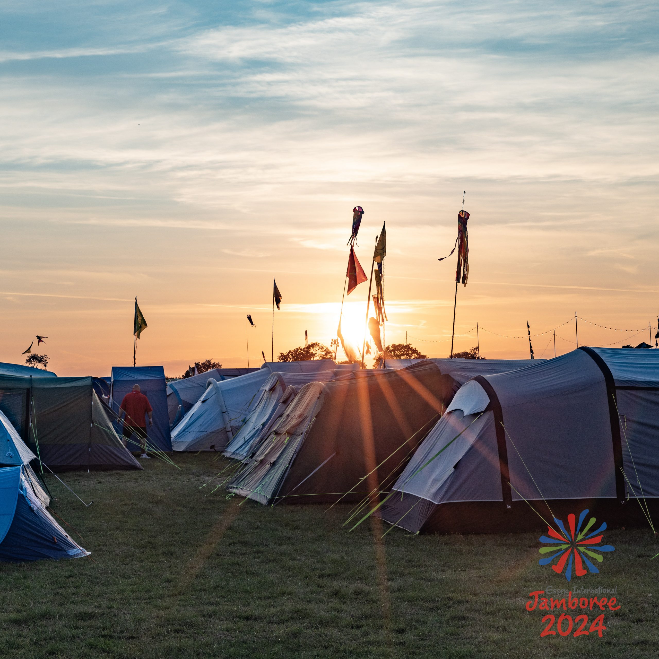 A field of tents, with the sun setting in the background.