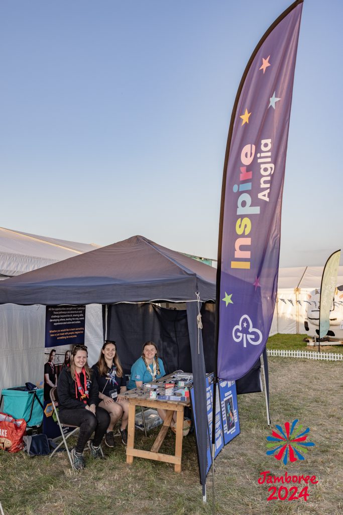 Three Inspire volunteers sit at an Inspire stand at EIJ