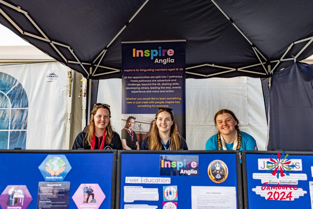 Three Inspire volunteers sit at an Inspire stand at EIJ - Photo by Steve Way