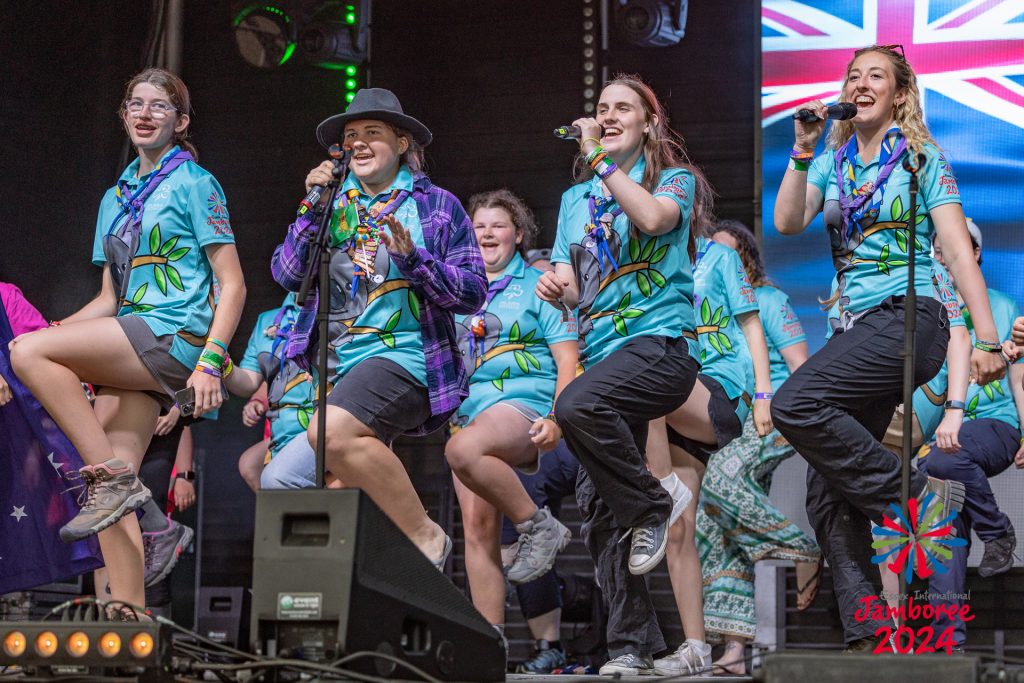 Participants from Australia dancing and singing on stage. 