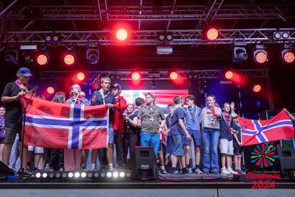 The Danish contingent getting ready to perform on stage. Two large flags are being held on either side. 