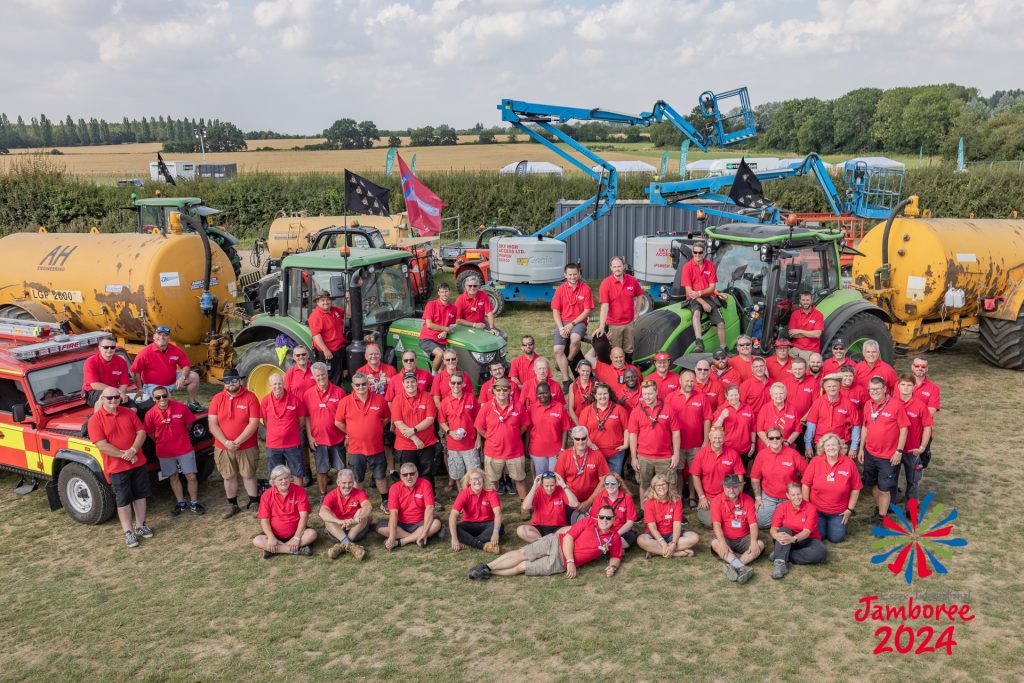 The facilities team, standing in front of and sitting on their tractors and machinery. 