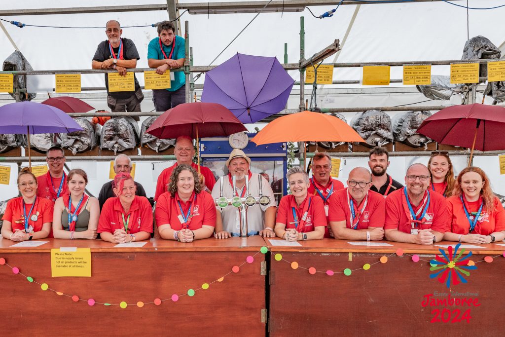 People standing behind a bar, holding umbrellas.