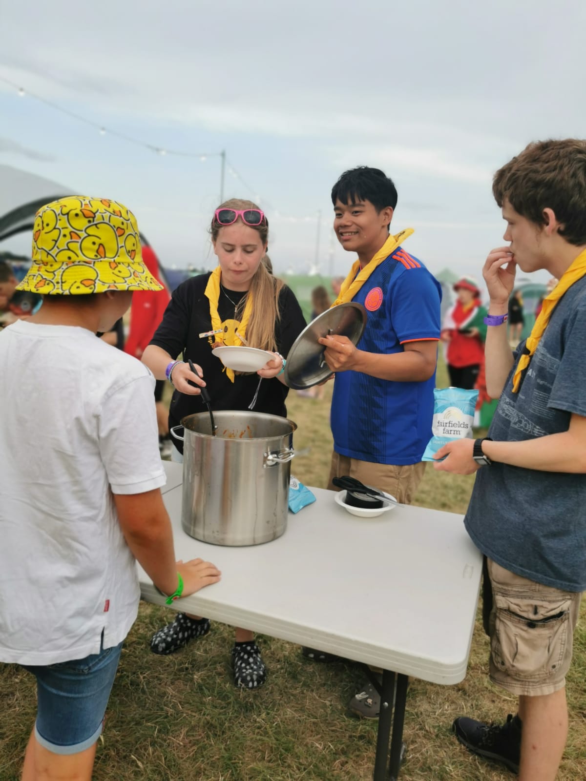 Participants surrounding a table with a pot of food.